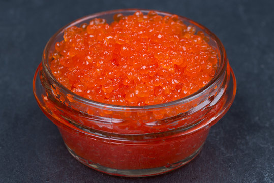 glass jar of red caviar on a dark background