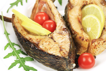 Grilled carp steaks with lemon and tomatoes.