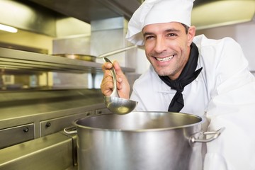 Smiling male cook tasting food in kitchen