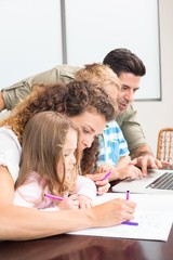 Attractive parents colouring and using laptop with their