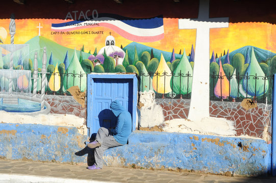 Man sitting near a mural at Ataco