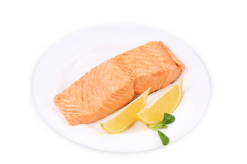 Fried salmon fillet on plate with lemon.