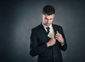 Man taking dollars banknotes with stealthy expression against gr