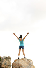 woman hiker cheering seaside mountain peak rock