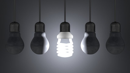 Glowing spiral light bulb, dead tungsten ones hanging on gray