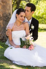 Groom kissing his beautiful bride at park
