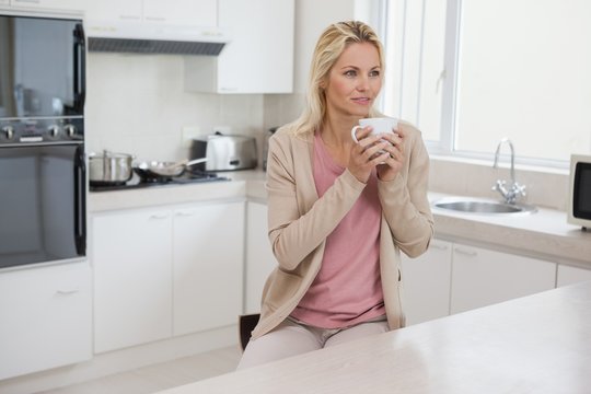 Thoughtful Woman Drinking Coffee In Kitchen