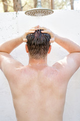 Man having shower outdoors. View from the back.