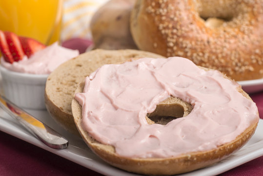 Freshly baked bagel with strawberry cream cheese, orange juice a