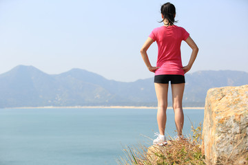 Fototapeta na wymiar hiking woman stand at seaside mountain peak rock 