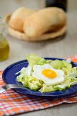 uova al tegamino con contorno d’insalata e cestino del pane
