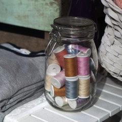 Fototapeta na wymiar Colorful threads in glass pot