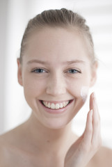 Attractive girl putting anti-aging cream on her face