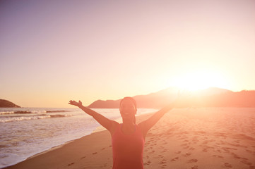 Fototapeta premium woman open arms at sunrise/sunset beach