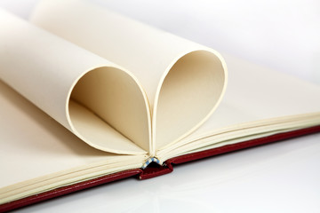 Blank opened notebook with sheets folded in form of a heart