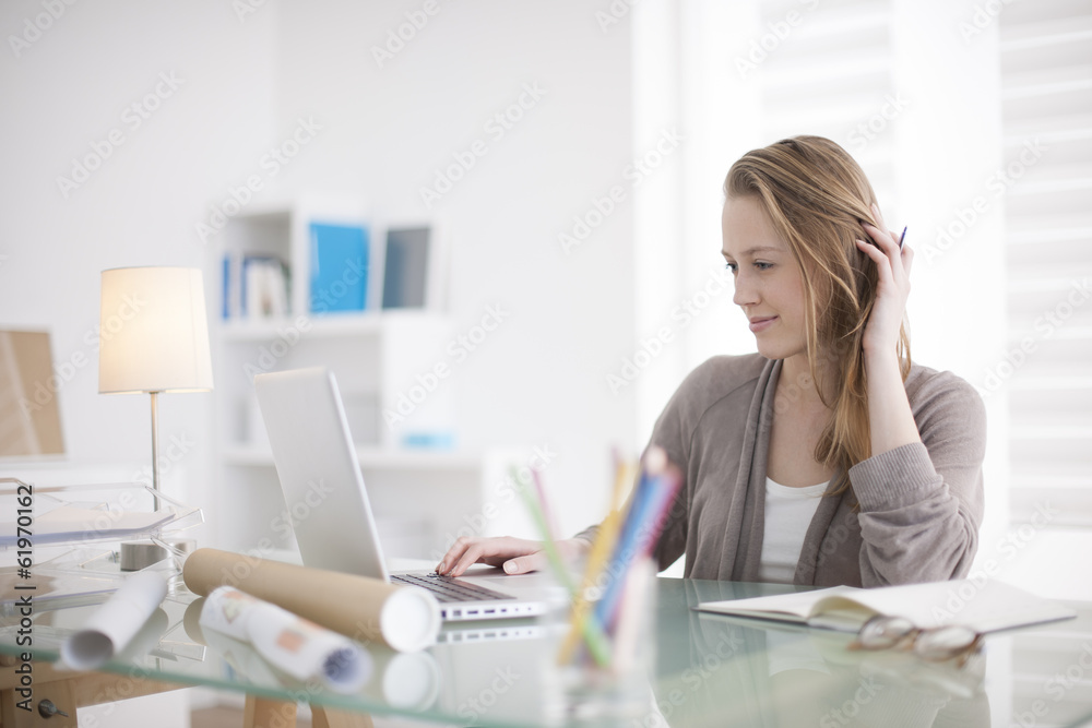 Wall mural beautiful young woman working on her laptop in her office