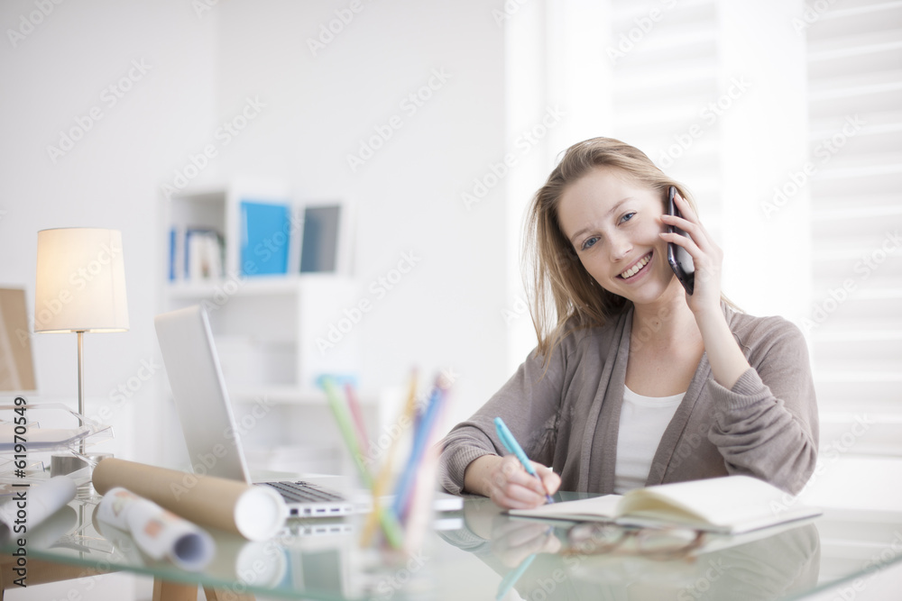 Wall mural beautiful young woman on the workplace using his phone