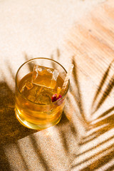 Whisky liqueur glass with ice cubes on the beach