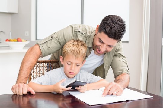 Smiling Father Helping Son With Math Homework At Table