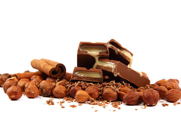 Stack of chocolate tiles with hazelnuts and cinnamon sticks.