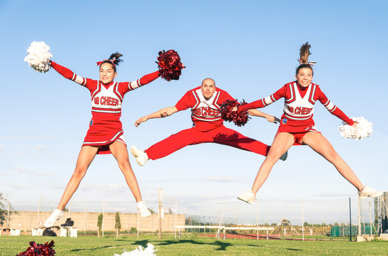 Cheerleaders team with male Coach performing a synchronized jump