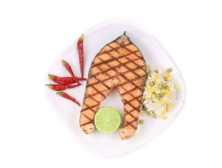 Grilled salmon steak with vegetables on plate.