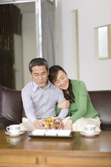 husband and wife sitting on sofa hold their arms