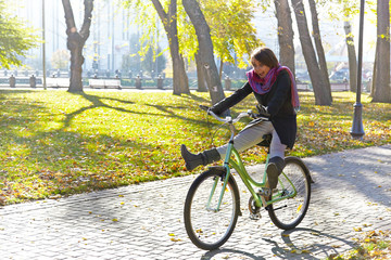 A young girl learns to ride a bicycle in autumn park. Backlight.