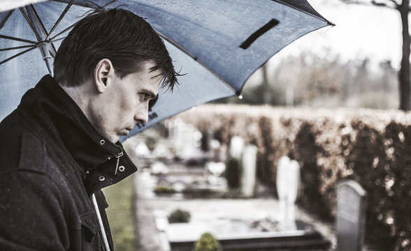 Man Mourning Over Loss At Grave Stone