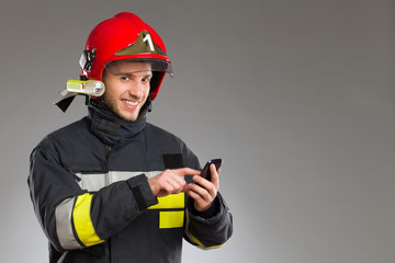 Firefighter using smart phone. - obrazy, fototapety, plakaty