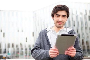 Portrait of a young relaxed men using tablet in the street