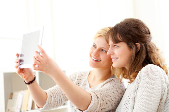 Girls on sofa taking selfie picture with tablet