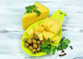 Parmesan cheese, fresh herbs and olives on wooden background