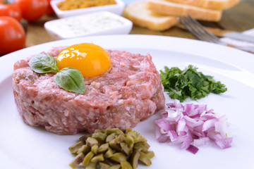 Delicious steak tartare with yolk on plate on table close-up