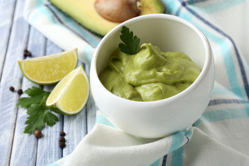 Fresh guacamole in bowl on wooden table
