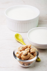 Two bowls with white cream and a bowl of cashew nuts