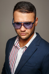 Serious man in sunglasses posing in the studio