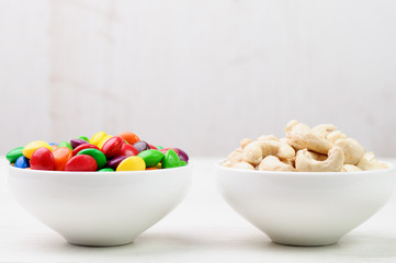 Cashew nuts and candies in bowls side by side