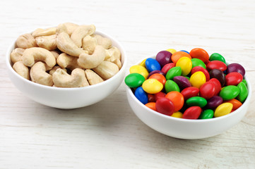 Two cups with cashew nuts and multicolor candies