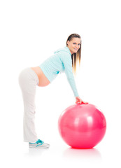 A young pregnant woman working out with a fitness ball