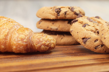 Fragment of a croissant next to chocolate chip cookies