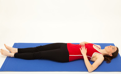 Die junge Frau macht Pilates Übungen auf einer Matte