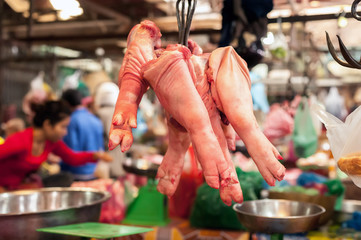 Raw pork legs for sale hanging at asian food market. Cambodia