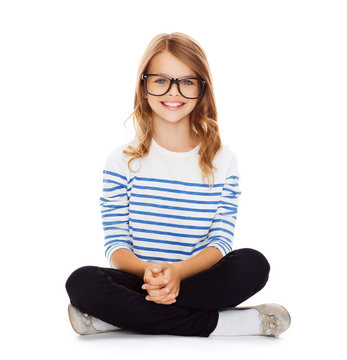 smiling girl in eyeglasses sitting on floor