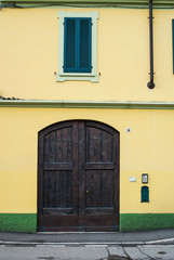 Facciata palazzo giallo e verde con portone di legno