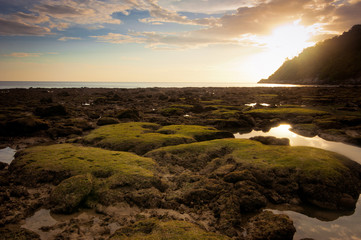Sunset at tropical beach with rocks and stones