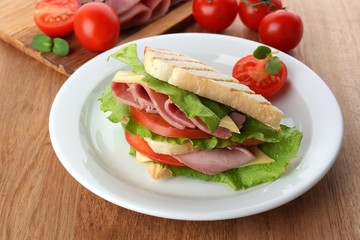 Tasty sandwich with ham on wooden table