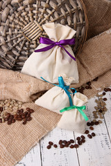 Sacks with coffee on wooden table, on sackcloth background