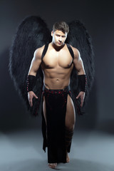 Handsome muscular guy posing as fallen angel