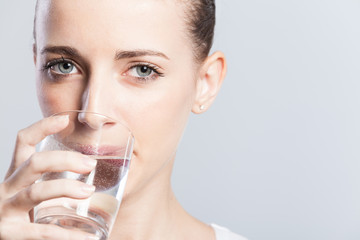 Young curly haired woman drinking water.